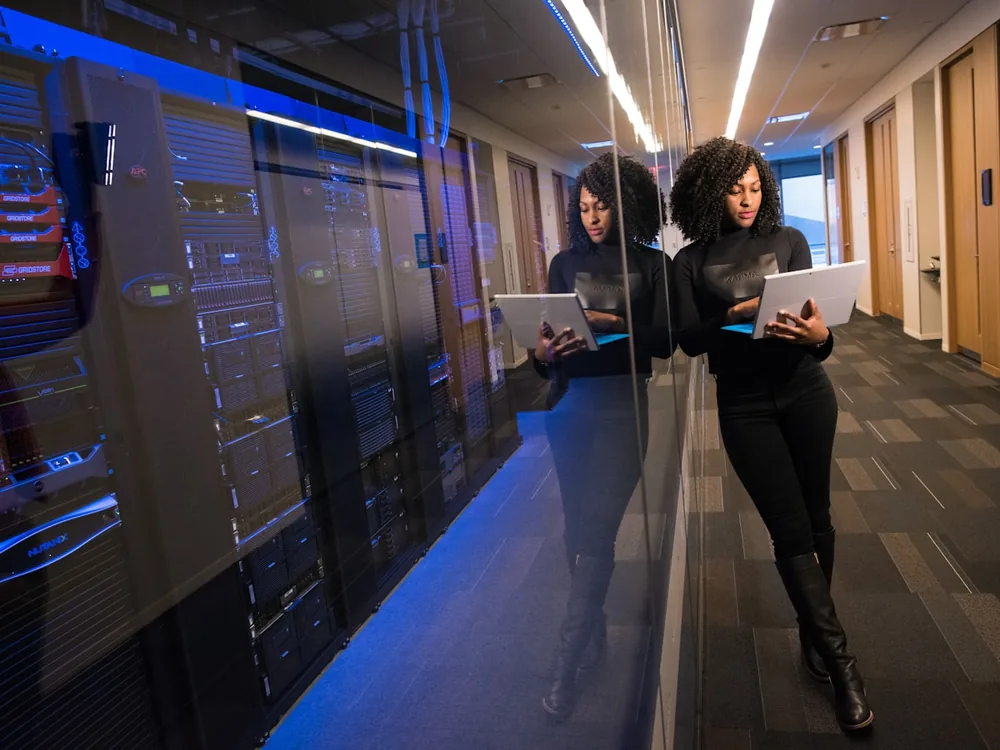 An engineer working on a laptop beside a rack of running servers