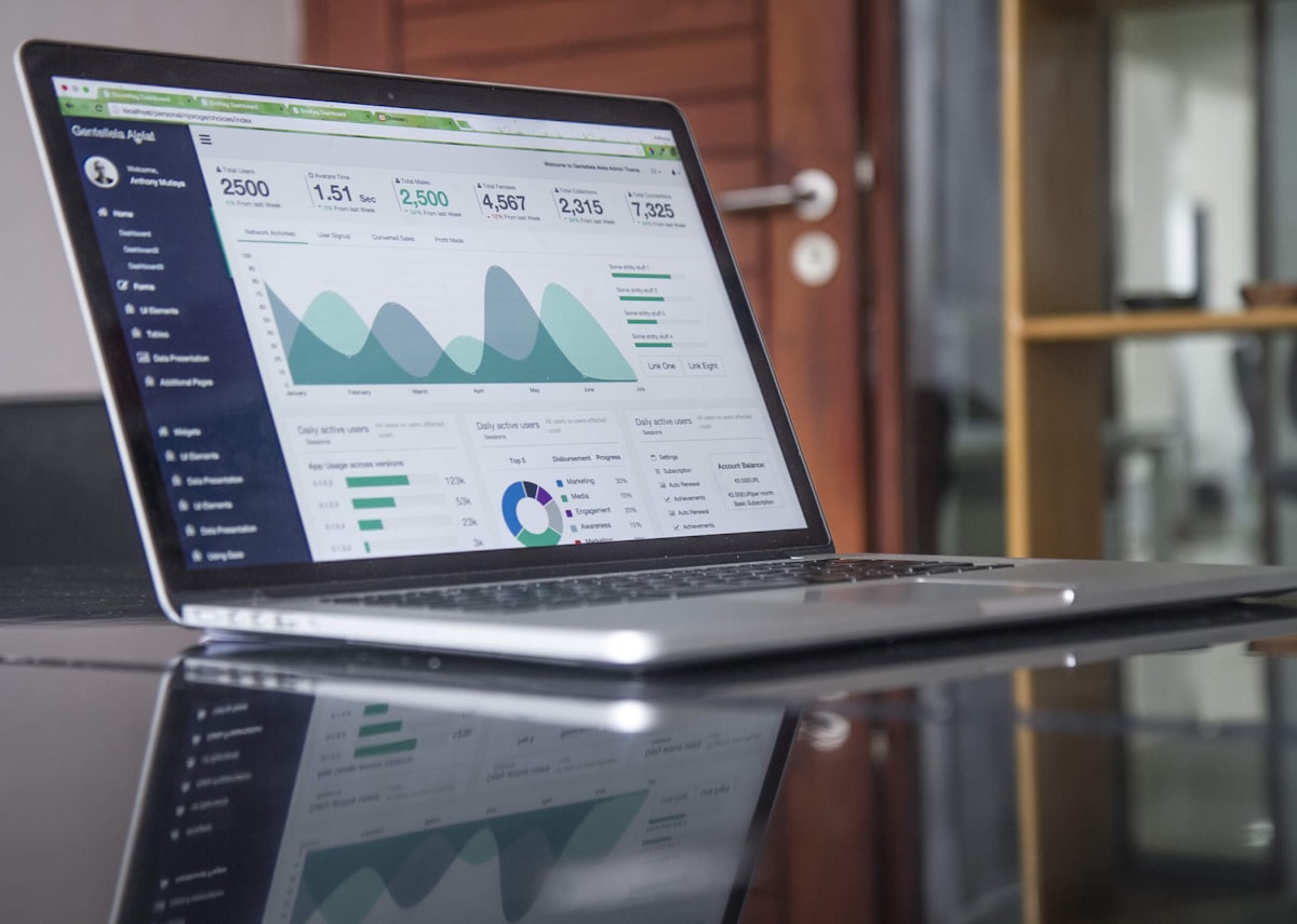 A laptop on a desk showing an analytics dashboard of charts and figures