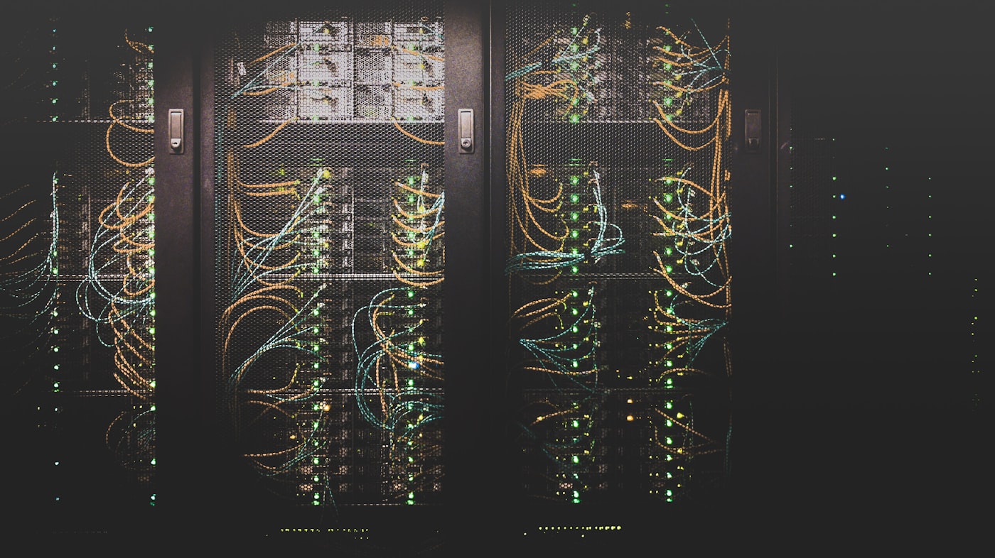 Server racks in a data centre, cabling lit by rows of green status lights