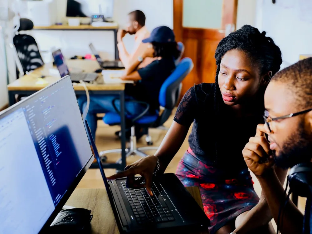 Two engineers reading code together at a laptop in an open office